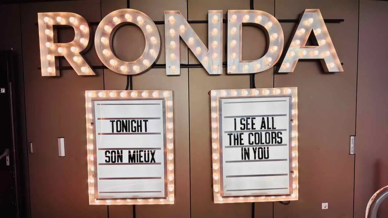 Zaal posters bij de Ronda: "Tonight SON MIEUX" en "I SEE ALL THE COLORS IN YOU"